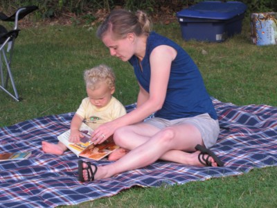Becca reading with Lijah on a blanket on the grass