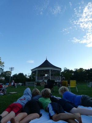 the boys and friends lying on a blanket watching a concert at the bandstand