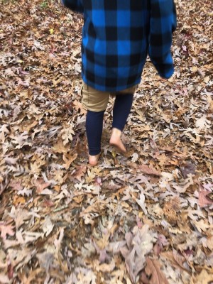 Zion walking barefoot in fall leaves wearing jacket and long underwear