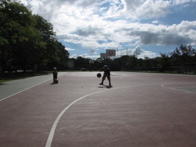 Harvey dribbling a basketball on an empty court, Lijah watching