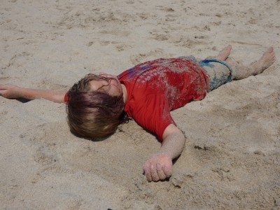 Elijah lying sandy on the beach