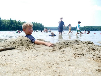 Elijah sitting comfortably in a hole in the sand at Walden Pond