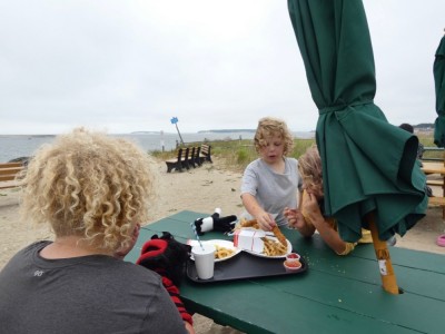 the boys eating fried food at a beach picnic table