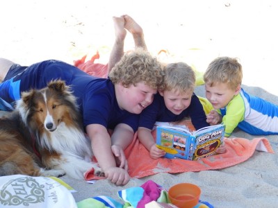 Zion reading a book to his brothers on the beach