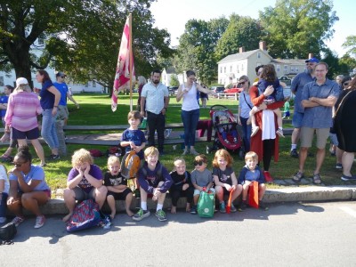 the boys and their friends sitting on the curb waiting for the parade