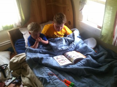Harvey and Zion sitting up in the bed together, reading a comic book