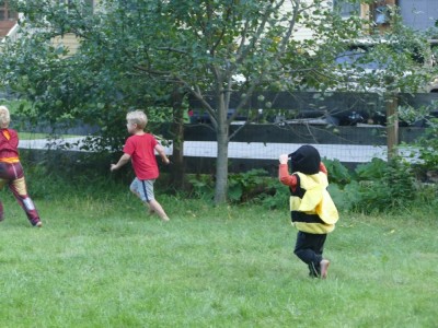 Lijah in a bee costume running after Zion in the yard