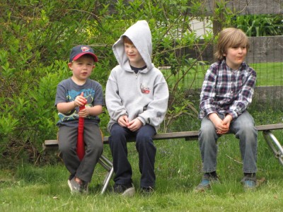 Zion, Nathan, and Eliot sitting on a bench--Zion with cap and bat