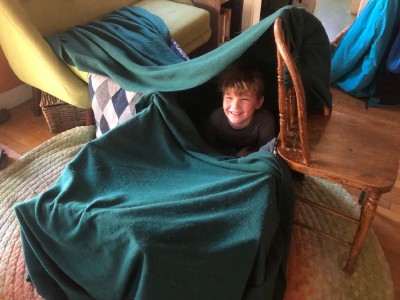 Elijah smiling from a blanket fort