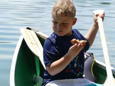 Zion eating a sandwich sitting in the canoe