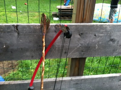 compound bow and homemade arrow, leaning against the fence