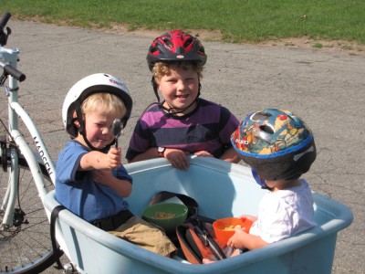 Zion and Lijah in the blue bike with cereal, Harvey standing behind it