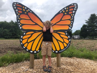 Elijah standing in front of giant butterfly wings being a butterfly