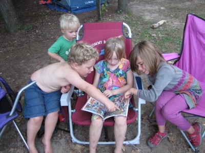 Harvey, Zion, and friends in camping chairs sharing a comic book