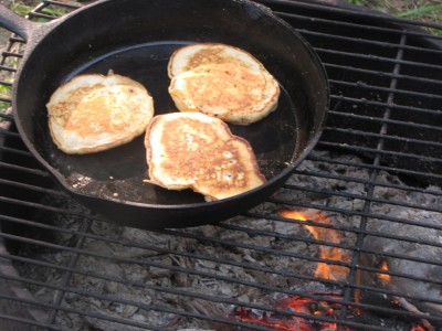 pancakes cooking in the skillet over the fire