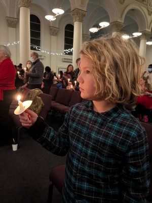 Elijah holding a lit candle at church
