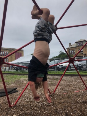 Elijah hanging upside down on a play structure
