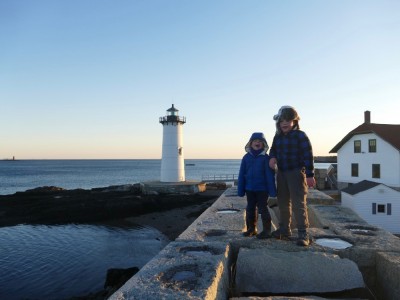 Harvey and Zion standing on a wall with a lighthouse in the background