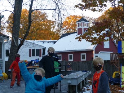 the boys bundled up celebrating with friends, orange leaves in the background