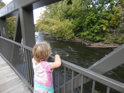 Elijah standing on a bridge looking at some slight rapids