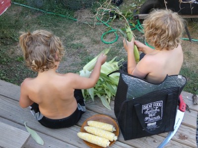 Zion and Elijah shucking corn on the back deck