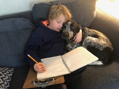 Zion writing while cuddling Blue on the couch