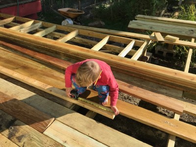 Lijah, with a pencil behind his ear, measuring wood for the new deck