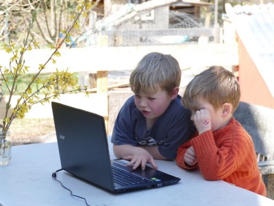 Zion and Lijah looking at the laptop out on the deck