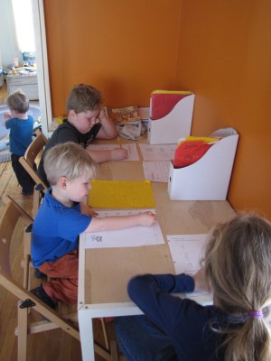 Harvey, Zion, and Havana doing homework at the unfinished playroom desk