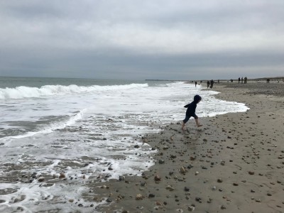 Lijah running away from the waves on a fairly crowded beach