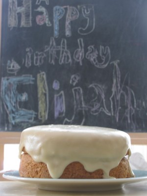 a birthday cake in front of a chalkboard birthday message