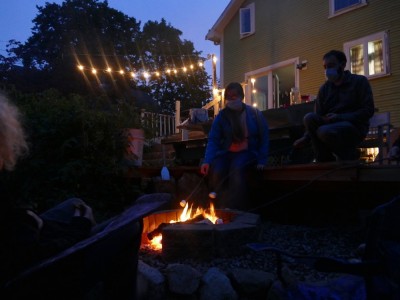 a fire, globe lights, and people in our backyard