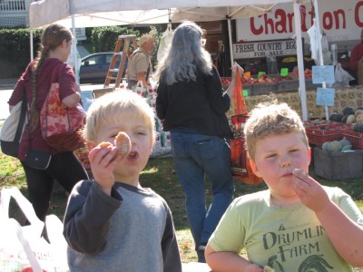 Harvey and Zion eating donuts in front of the Charlton Orchard stand