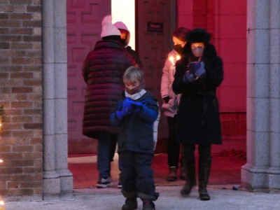 Elijah and Mama sheltering candles at the outdoor Christmas Eve service
