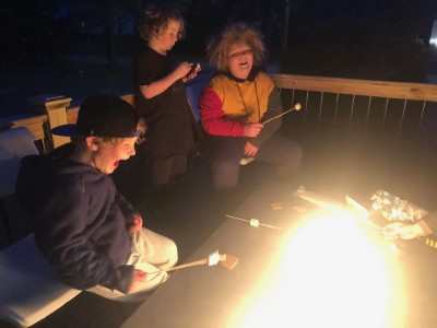 the kids toasting marshmallows and laughing around a friend's fire table