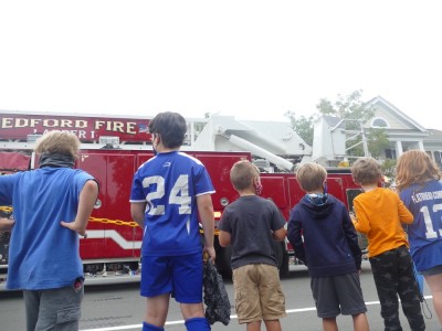 the boys and other kids watching a fire truck in the Bedford Day parade