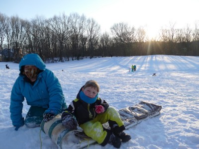 Harvey and Lijah resting on the toboggan on top of a sled hill