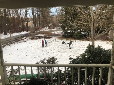 the boys kicking a flat yoga ball in the snowy yard