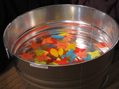 paper shapes floating in a tin basin of water