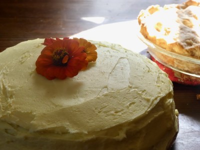 a yellow-frosted cake with flowers on top of it