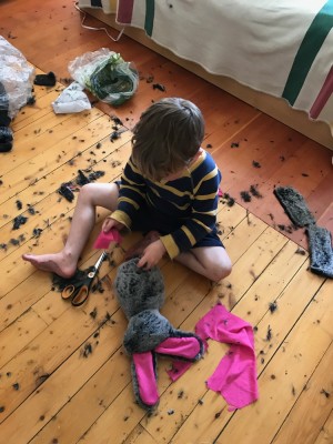 Lijah sitting on the bedroom floor with a half-made stuffed bunny, surrounded by fur debris