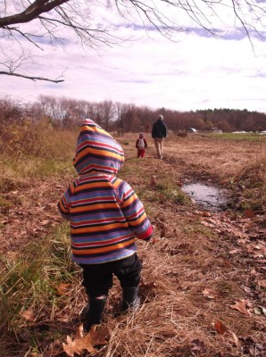 Zion in a field, hood up, looking at Dada and Harvey ahead of him