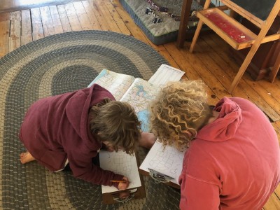 Harvey and Zion looking at an atlas on the rug