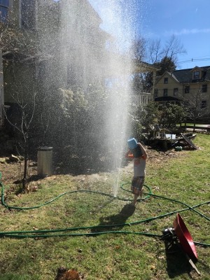 Lijah playing in the spray from a hole in the hose