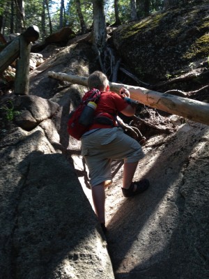Harvey climbing up steep boulders in a dark gorge