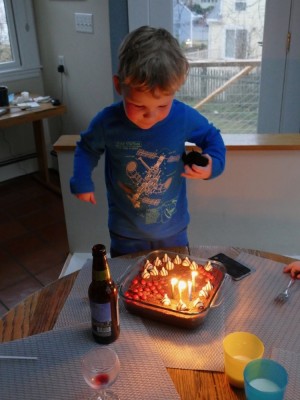 Lijah blowing out the birthday candles on the cake grandma made him
