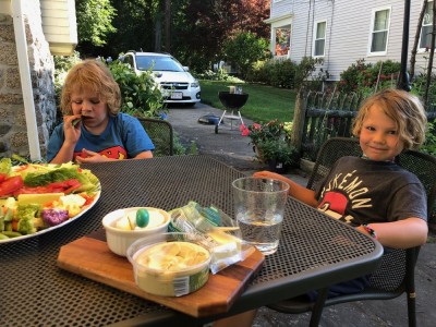 Zion and Elijah eating veggies at Grandma's outside table