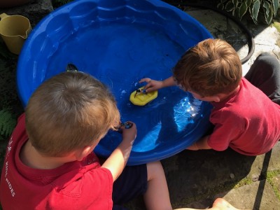Zion and Lijah playing with boats in a wading pool