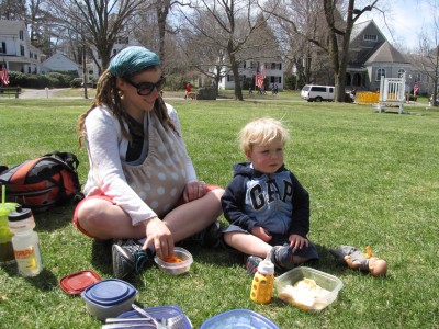Mama and Zion sitting on the grass surrounded by containers of food