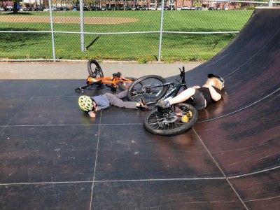 Harvey and Elijah resting in the sun by their bikes on the halfpipe